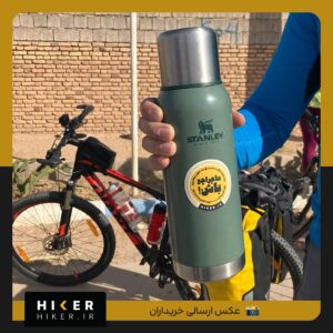 استیکر ضد آب زرد و مشکی با نوشته فارسی ماجراجوباش برند هایکر روی فلاسک سبز استنلی