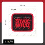 برچسب ضد آب مستطیلی با حاشیه قرمز و پس‌زمینه مشکی که روی آن عبارت انگلیسی Whatever Happens Stay Wild با فونت کالیگرافی قرمز به سبک پاشش مایع یا رنگ طراحی شده است. مناسب شیشه ماشین آفرود و موتور