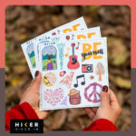 چند صفحه استیکر شیت با موضوع یوگا، سفر، عکاسی و انگیزشی در دستان یک زن در طبیعت