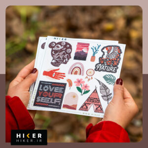 شیت استیکر با طرح‌های متنوع طبیعت و بوهو شامل کوهستان، گل، برگ، کاکتوس، چادر، نمادهای تزئینی و تایپوگرافی الهام‌بخش در دستان یک زن در طبیعت پاییزی