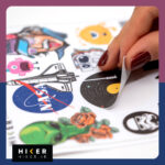 مجموعه‌ای از برچسب‌ها شامل: فضانوردی که روی یک سیارک در حال مدیتیشن است، بادکنک‌هایی به شکل سیارات منظومه شمسی در دست یک فضانورد کوچک، سرهای بیگانه سبز، جمجمه‌های فانتزی شکسته، و یک هیولای تک‌چشم صورتی مناسب موبایل