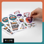 شیت استیکر با تم صخره‌نوردی حاوی تصاویر: دختر صخره‌نورد در حال صعود، هارنس سنگ‌نوردی، طناب گره‌خورده، ابزار حمایت، و استیکر تایپوگرافی Just Do It با فونت گرافیتی و رنگ نارنجی.